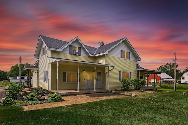 back of house featuring covered porch, cooling unit, and a lawn