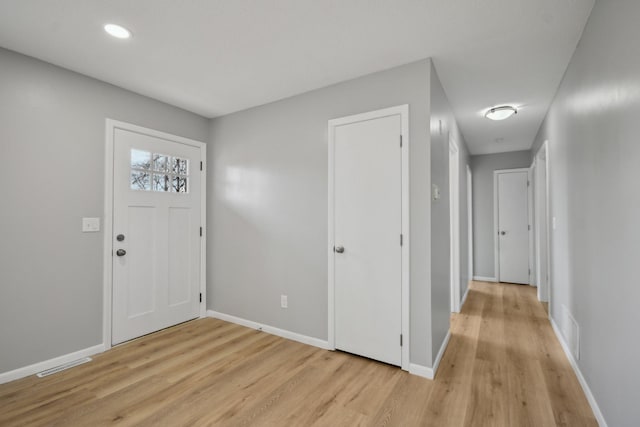 foyer entrance with light wood-type flooring, visible vents, and baseboards