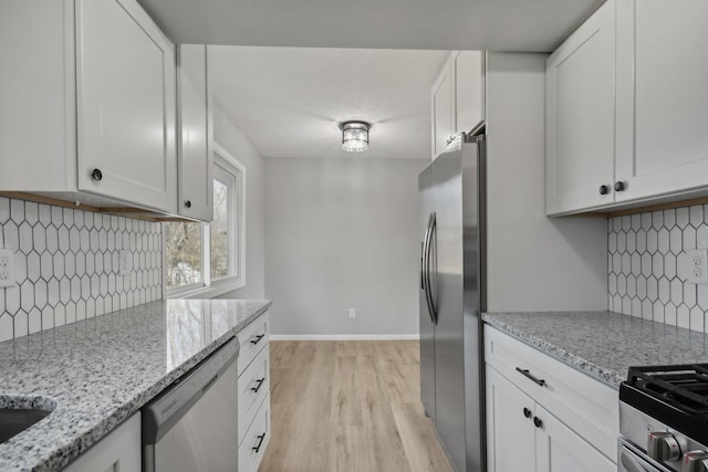 kitchen featuring baseboards, stainless steel appliances, light wood-style floors, and white cabinets