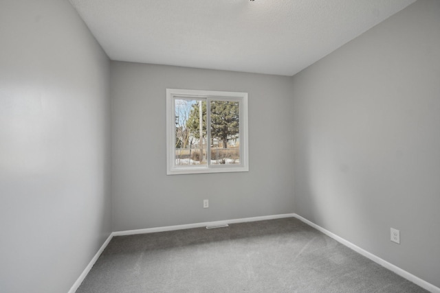 empty room with carpet flooring, visible vents, and baseboards