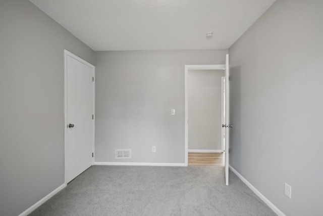 spare room with baseboards, visible vents, a textured ceiling, and carpet flooring