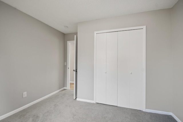 unfurnished bedroom featuring carpet, baseboards, and a closet