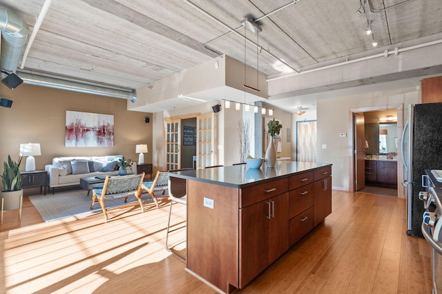 kitchen featuring a breakfast bar area, a kitchen island, light wood-style floors, open floor plan, and dark countertops