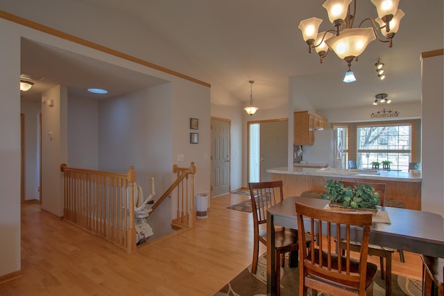 dining area featuring lofted ceiling, light wood-style flooring, and a notable chandelier