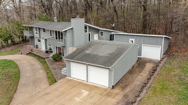 1509 Woodland Dr SW, Rochester, MN 55902 - view of front facade featuring a view of trees, roof with shingles, a balcony, and a chimney