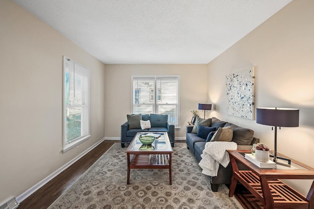 living area with visible vents, a textured ceiling, baseboards, and wood finished floors