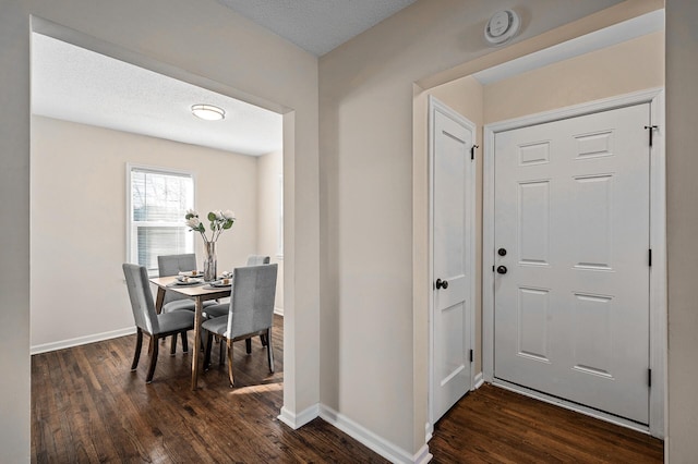 entrance foyer featuring a textured ceiling, dark wood finished floors, and baseboards