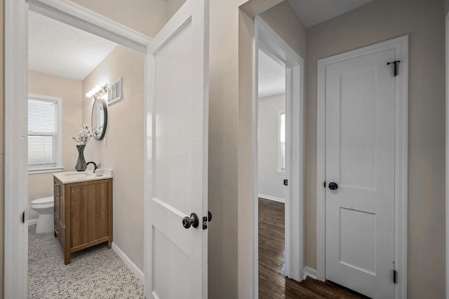 bathroom with baseboards, visible vents, toilet, wood finished floors, and vanity