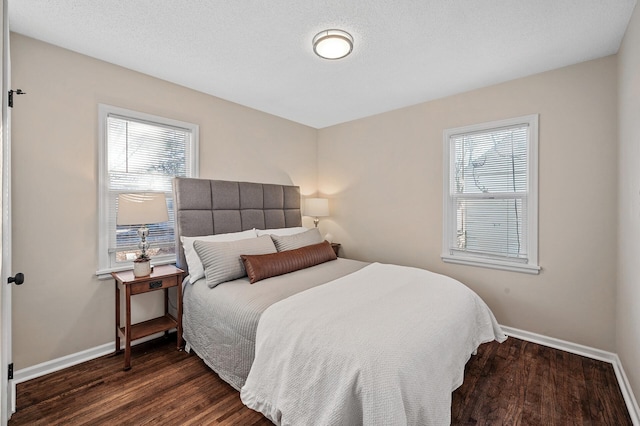 bedroom featuring a textured ceiling, multiple windows, dark wood finished floors, and baseboards