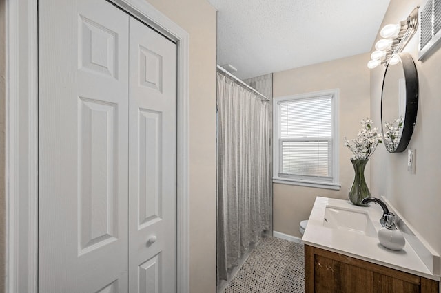 full bathroom featuring a closet, toilet, vanity, a textured ceiling, and baseboards