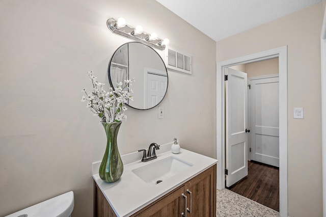 bathroom featuring toilet, visible vents, wood finished floors, and vanity