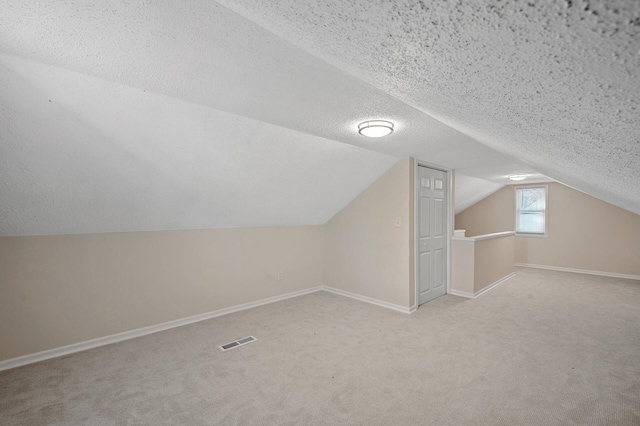 bonus room featuring a textured ceiling, light carpet, visible vents, and baseboards