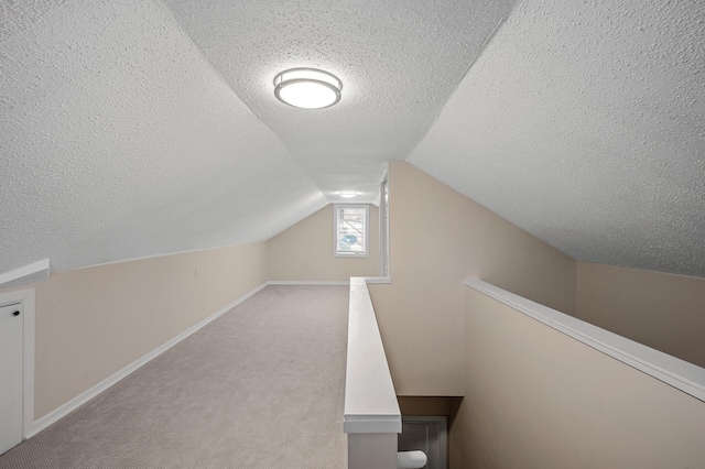 bonus room featuring carpet floors, lofted ceiling, a textured ceiling, and baseboards