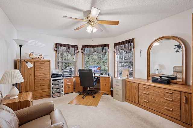 home office with light carpet, a textured ceiling, and a ceiling fan