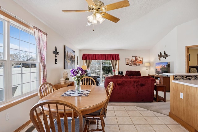 dining area featuring a ceiling fan, vaulted ceiling, a textured ceiling, and light tile patterned floors