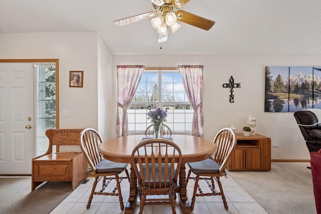 dining space featuring a textured ceiling, ceiling fan, light tile patterned floors, and light carpet