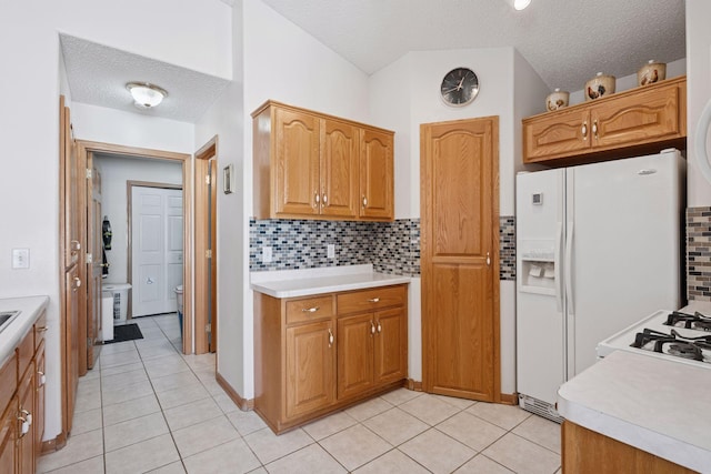 kitchen featuring brown cabinets, light countertops, backsplash, and a textured ceiling