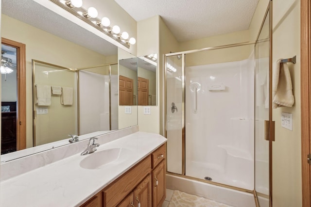 full bathroom featuring a shower stall, a textured ceiling, and vanity