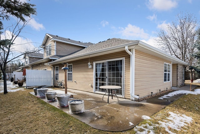 rear view of house featuring roof with shingles, a patio area, and fence