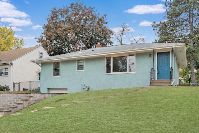 rear view of property with entry steps, a yard, a chimney, and stucco siding