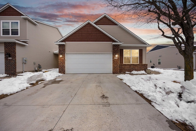 view of front of house with a garage, brick siding, and driveway