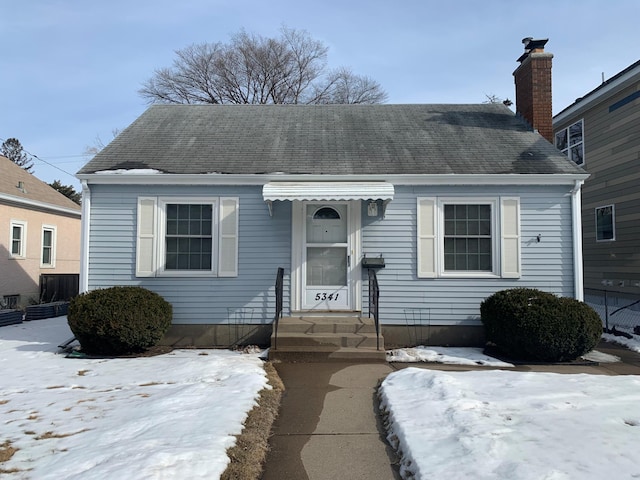 view of front of home featuring entry steps, a shingled roof, and a chimney