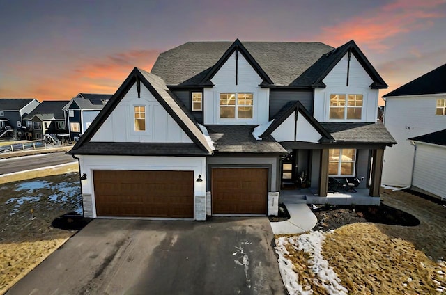 view of front of property featuring a garage, driveway, a shingled roof, a residential view, and board and batten siding