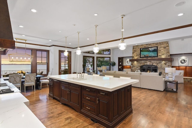 kitchen with pendant lighting, a fireplace, light countertops, a sink, and wood finished floors