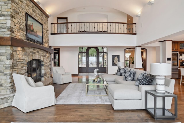 living area featuring lofted ceiling, a stone fireplace, and wood finished floors