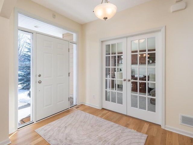 foyer entrance with baseboards, visible vents, wood finished floors, and french doors