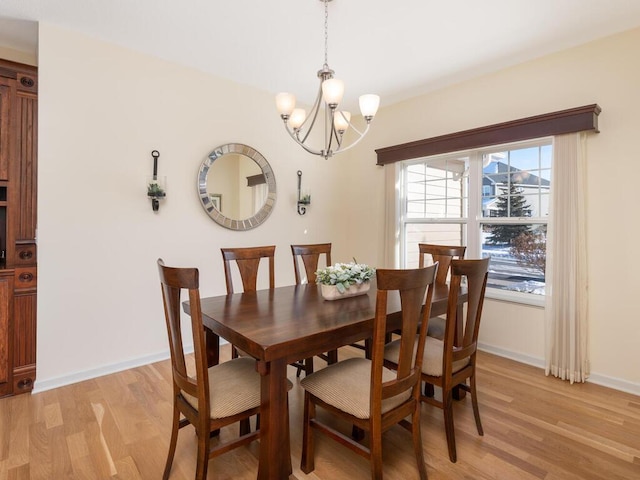 dining area featuring light wood finished floors, baseboards, and a notable chandelier