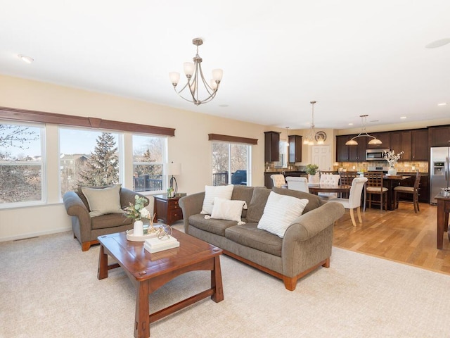 living area with baseboards, light wood-style floors, recessed lighting, and an inviting chandelier