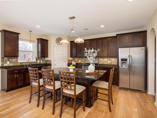 kitchen featuring stainless steel appliances, a center island, dark brown cabinetry, and light wood-style flooring