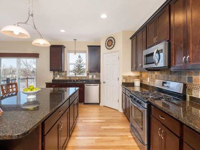 kitchen featuring light wood finished floors, appliances with stainless steel finishes, plenty of natural light, and a sink