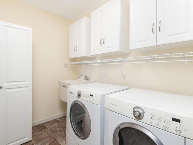 clothes washing area with separate washer and dryer, cabinet space, and baseboards