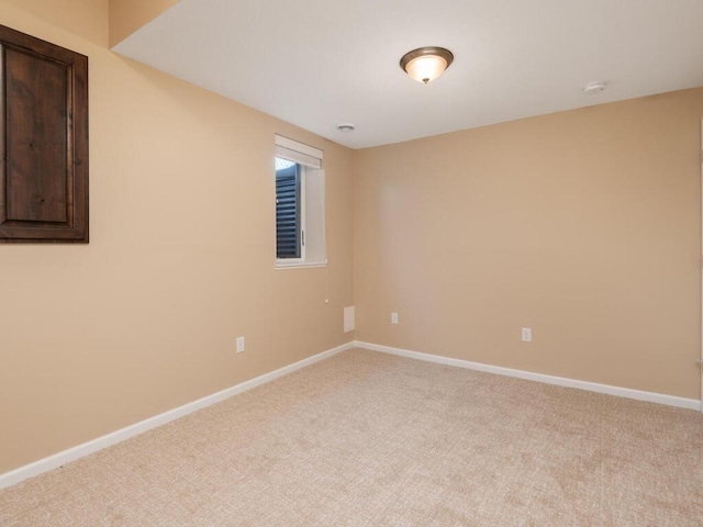 spare room featuring light colored carpet and baseboards