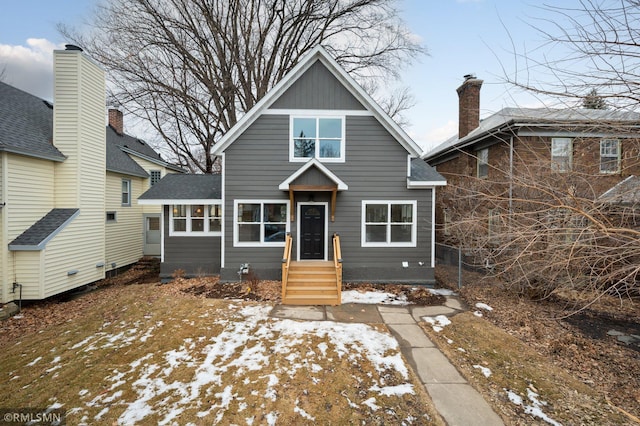 view of front facade with entry steps and a shingled roof