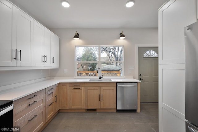 kitchen featuring stainless steel appliances, white cabinets, light countertops, and a sink