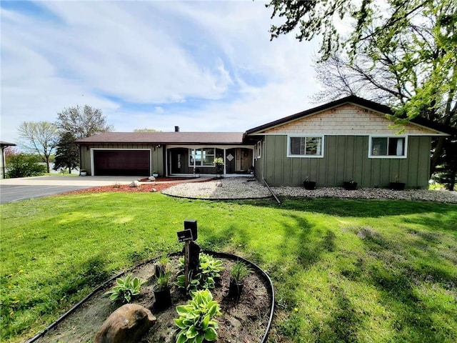 ranch-style house with board and batten siding, a front yard, driveway, and a garage