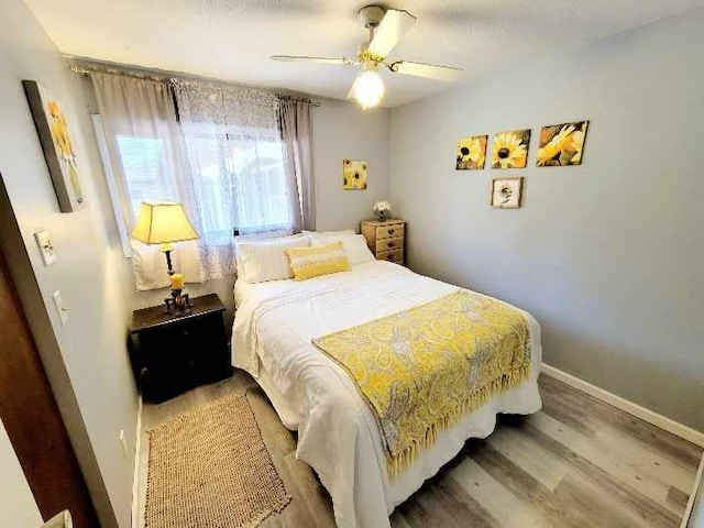 bedroom with wood finished floors, a ceiling fan, and baseboards