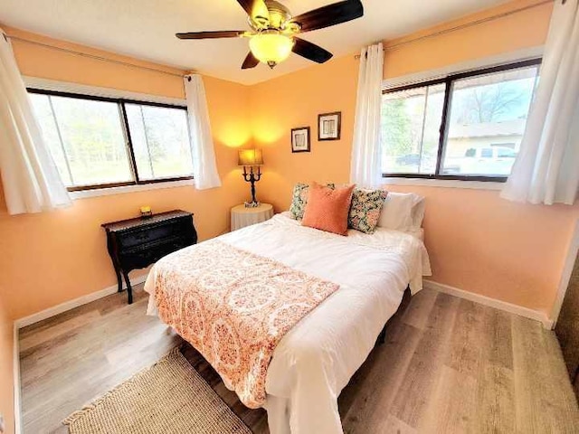 bedroom featuring light wood-type flooring, a ceiling fan, and baseboards