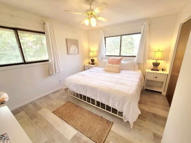 bedroom featuring baseboards, ceiling fan, visible vents, and light wood-style floors