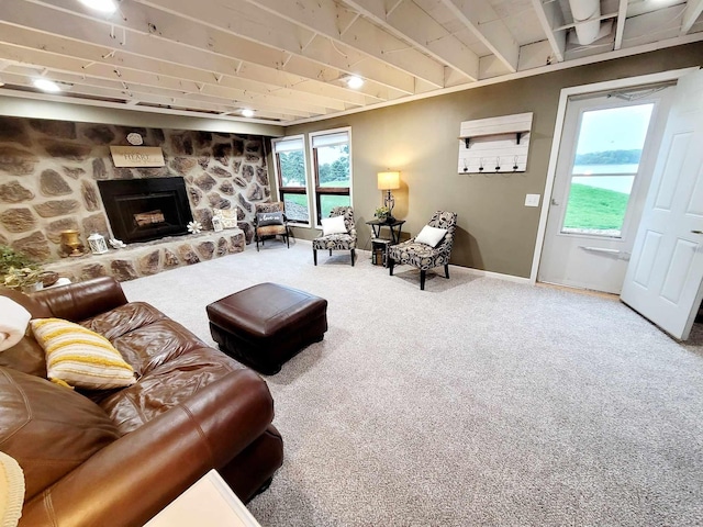 living room with carpet floors, a stone fireplace, and baseboards