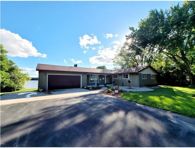 ranch-style house featuring concrete driveway, a front lawn, and an attached garage