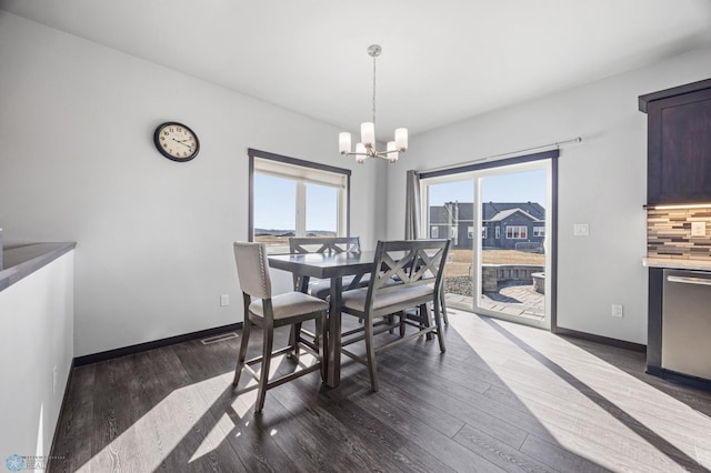 dining space featuring dark wood-type flooring, visible vents, a notable chandelier, and baseboards