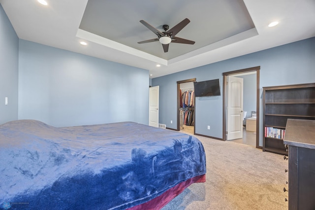 carpeted bedroom featuring a walk in closet, a raised ceiling, and recessed lighting