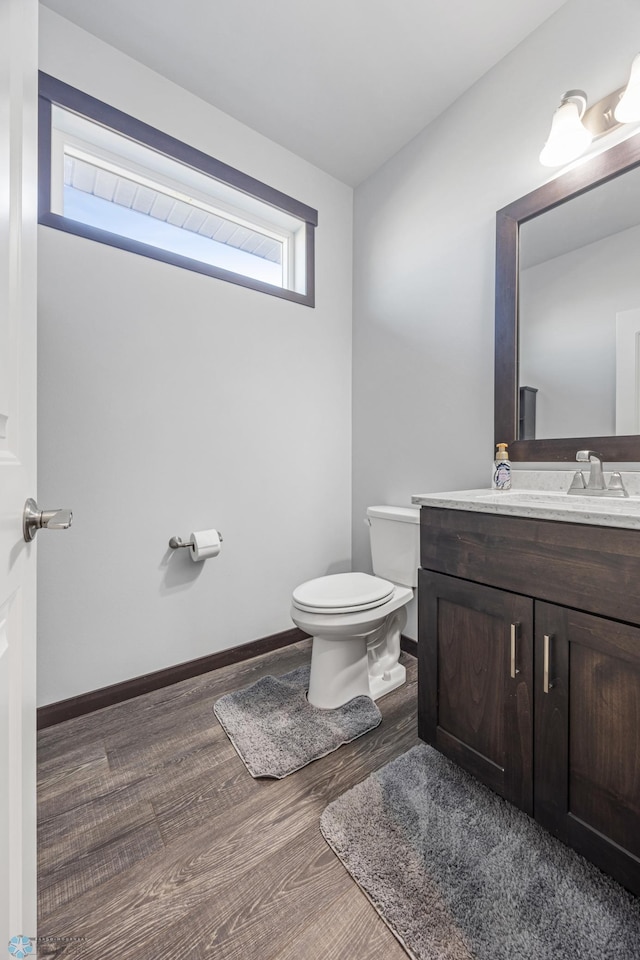 bathroom featuring baseboards, vanity, toilet, and wood finished floors