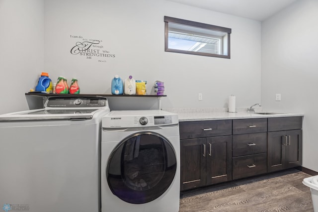 laundry room featuring wood finished floors, washer and clothes dryer, a sink, and cabinet space