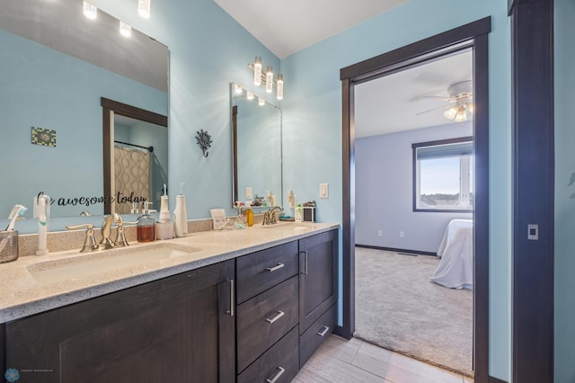 full bath featuring double vanity, ceiling fan, connected bathroom, and a sink