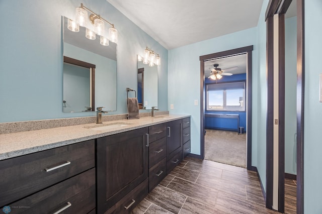 full bathroom featuring ceiling fan, double vanity, a sink, and baseboards